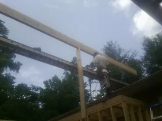 Carpenter setting a ridge beam over a new addition frame — Ice Dam Removal by Roofing Brothers in Goddard