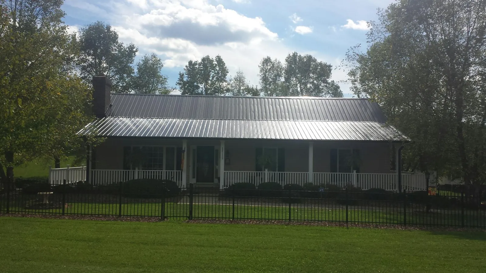 Gray metal roof on a brick ranch with a full width front porch — Gutter Guard Installation work by our crew in Goddard