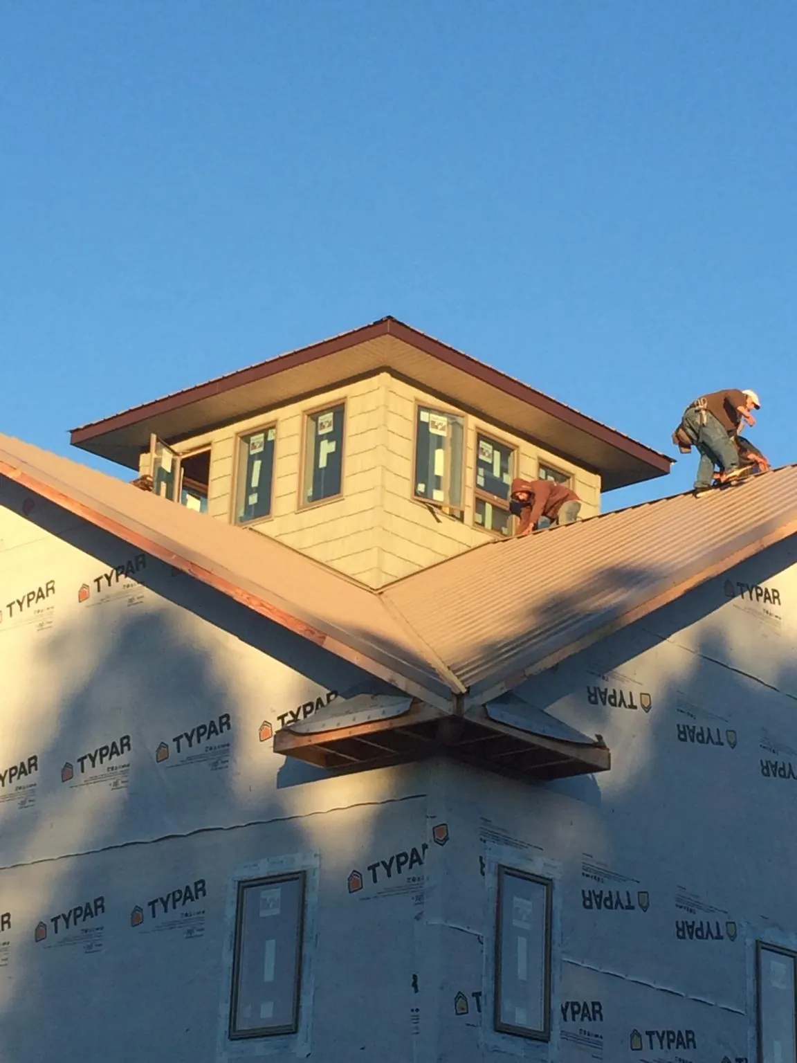 Roofers working around a rooftop cupola on a new metal roof at sunset — Roof Waterproofing in Goddard by Roofing Brothers